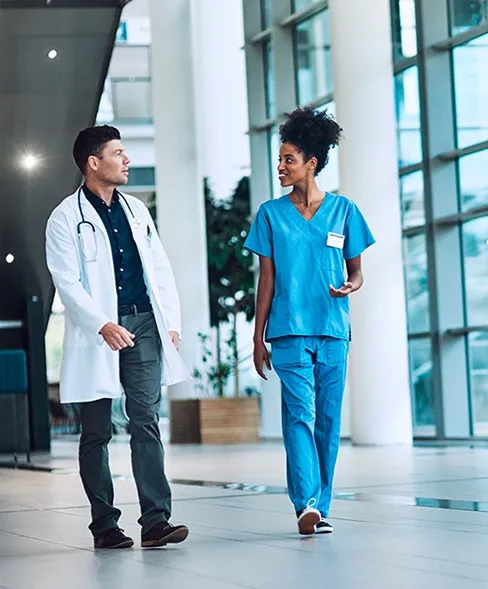 Two healthcare professionals walking and talking with one another